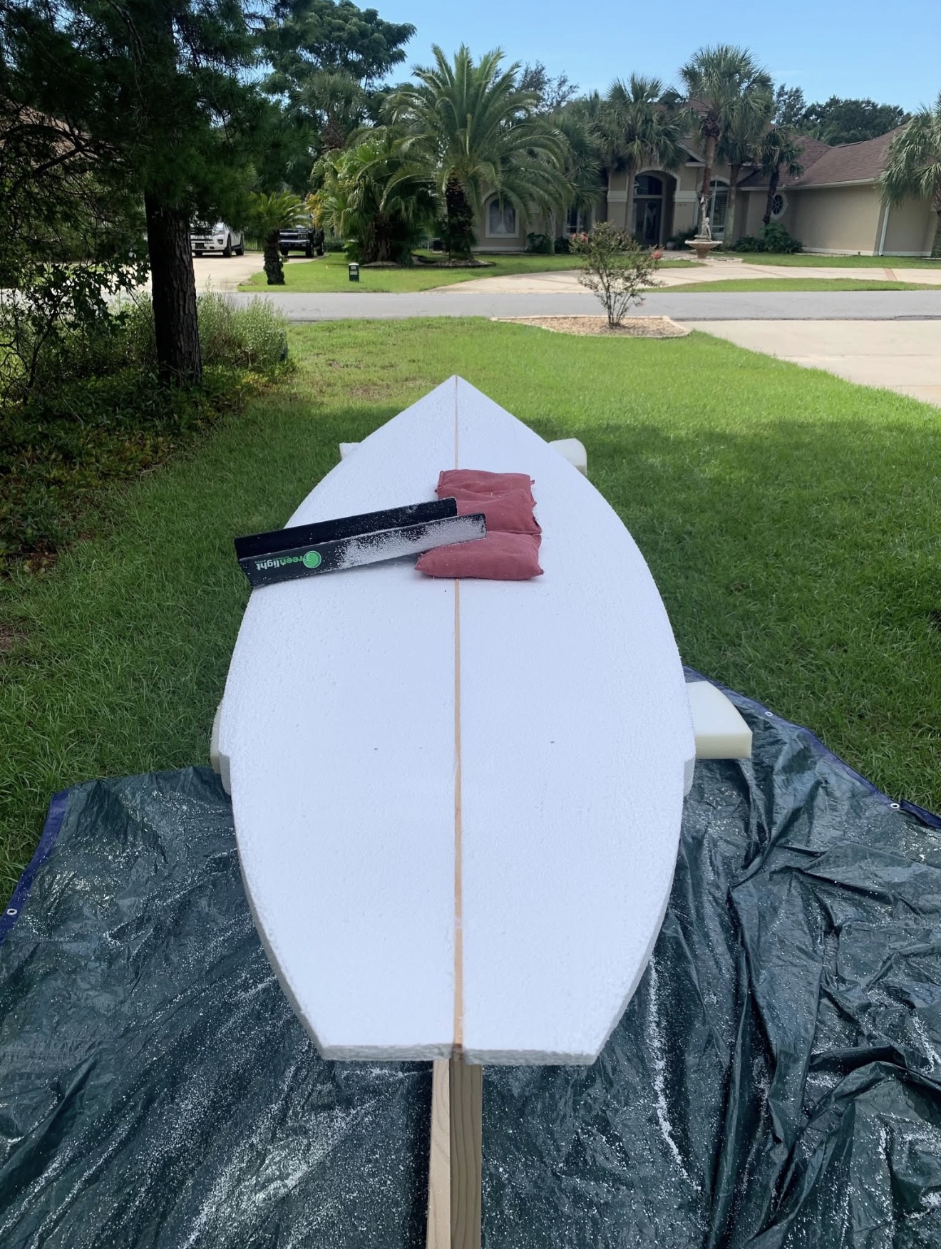 A shaped foam blank on a stand in the yard, mid-build
